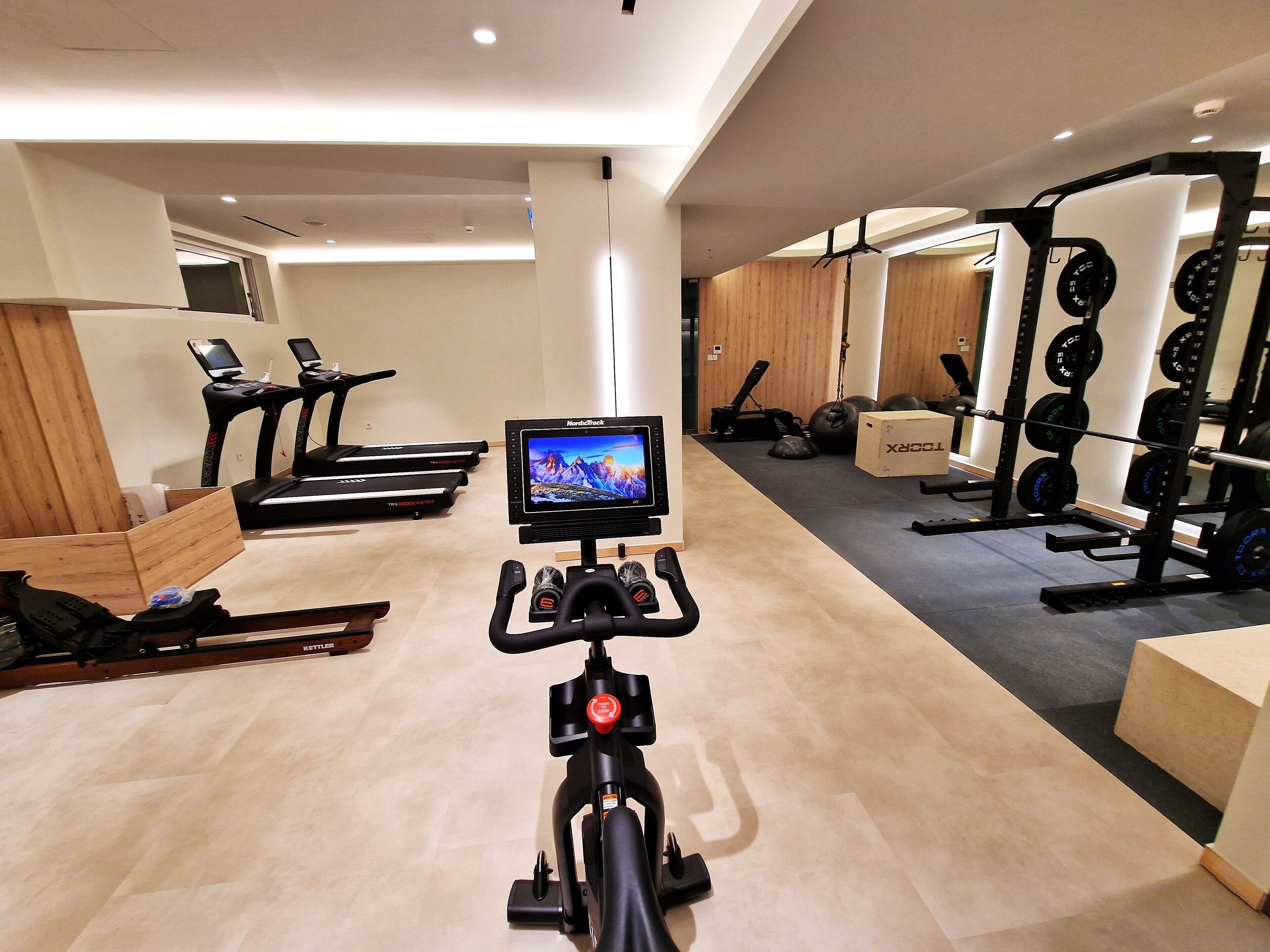 Un gimnasio con cintas de correr, una bicicleta estática y equipo de levantamiento de pesas.