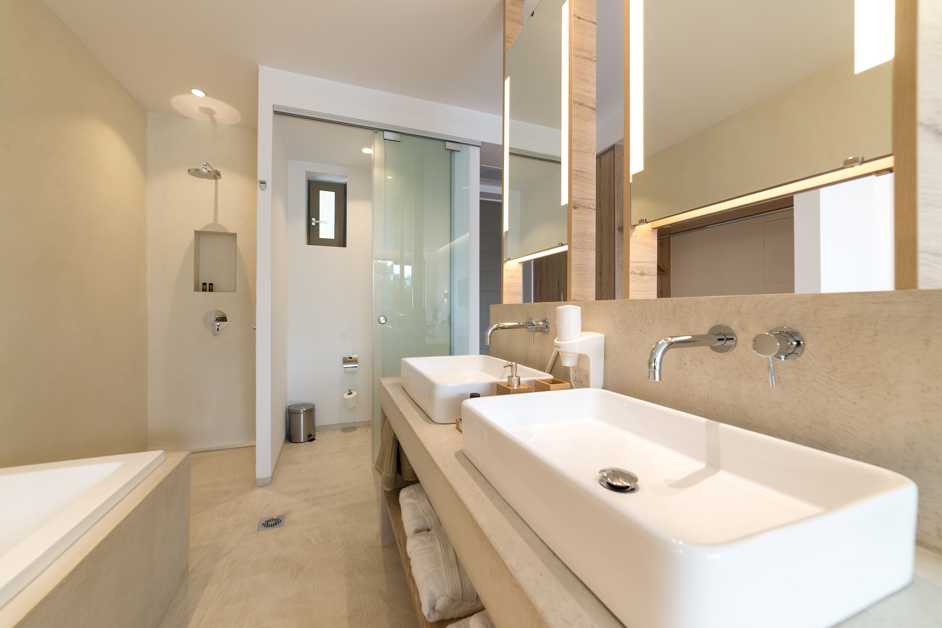 A modern bathroom with a large bathtub, a separate shower area, and a vanity with a mirror.