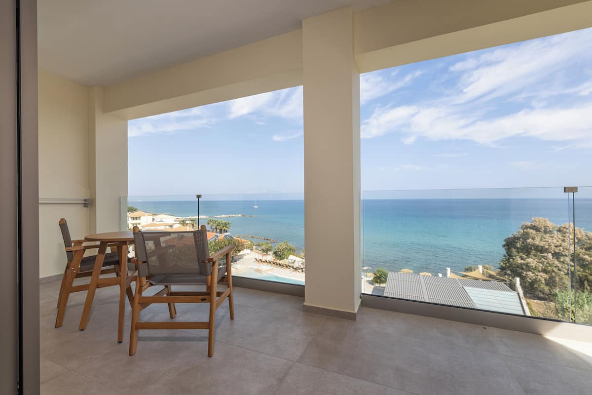 Un balcón con vistas al mar y una zona de comedor con mobiliario de madera.