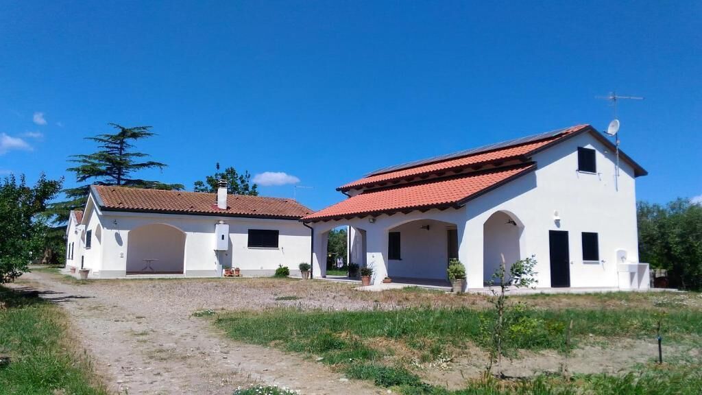 A white building with a red-tiled roof, a satellite dish, and a clear sky.