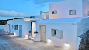 A row of white buildings with a flat roof, a central door, and small windows. - Ariana Eco Suites - Adults Only (Santorini)