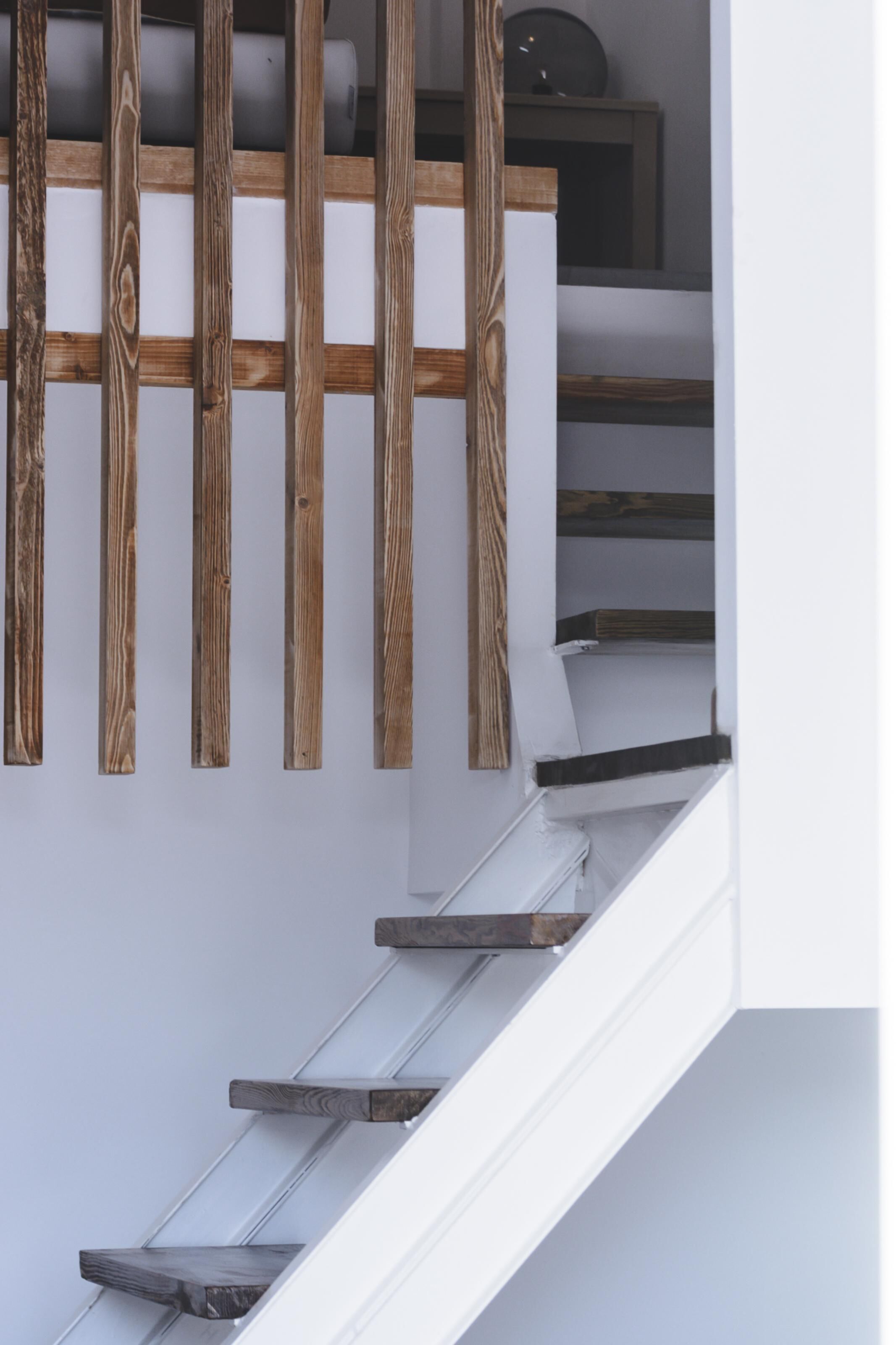 Una escalera con barandillas de madera y paredes blancas.