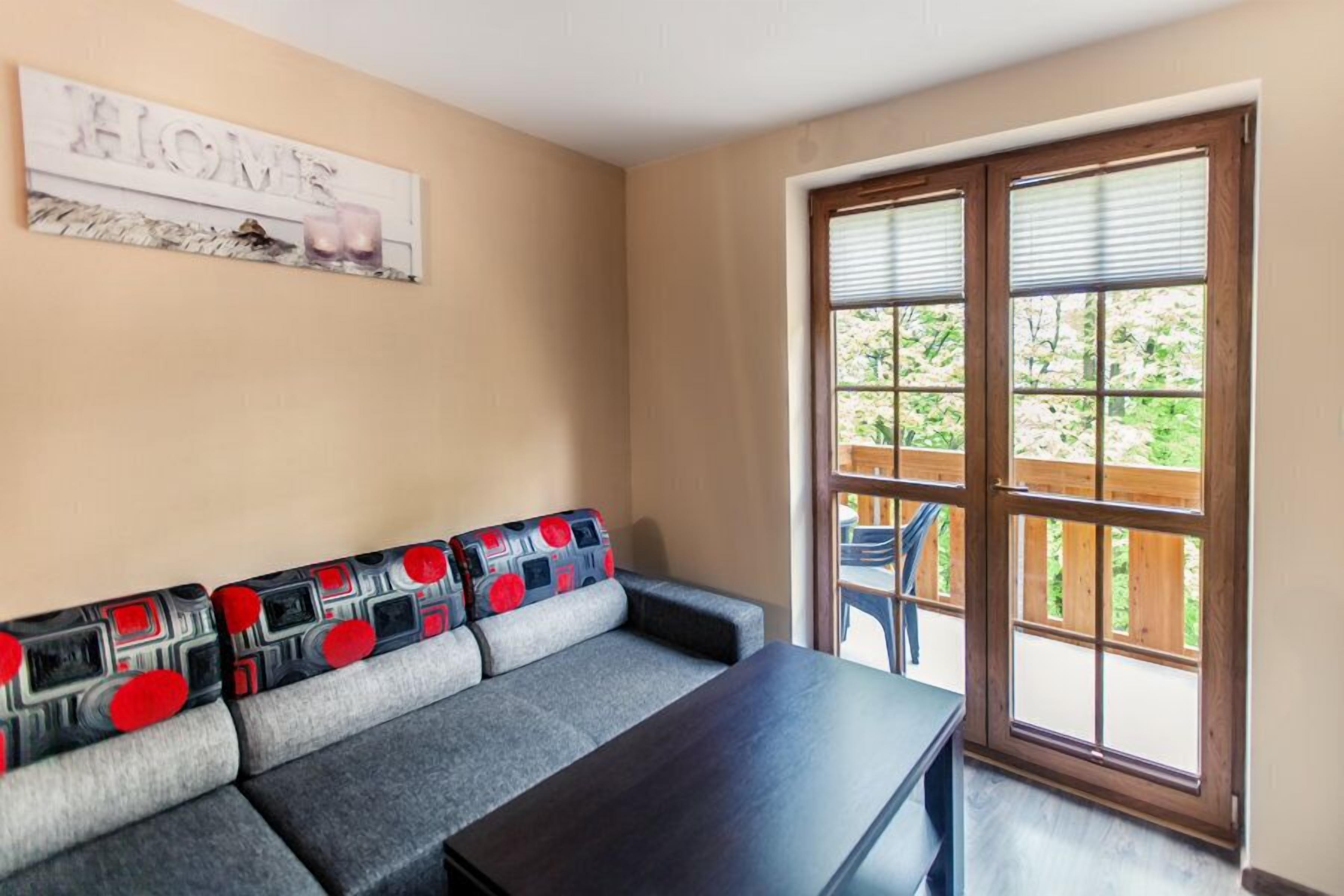 Een kamer met een bank, een tafel en een groot raam met zonwering.
