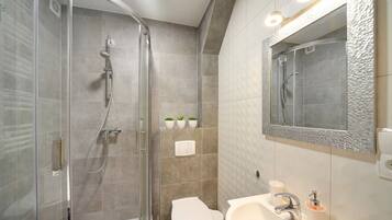 A modern bathroom with a glass-enclosed shower, a toilet, and a sink with a mirror.