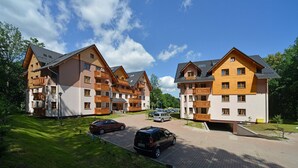 A residential building with multiple balconies, a paved driveway, and parked cars. - EverySky Lesny Dom (Karpacz)