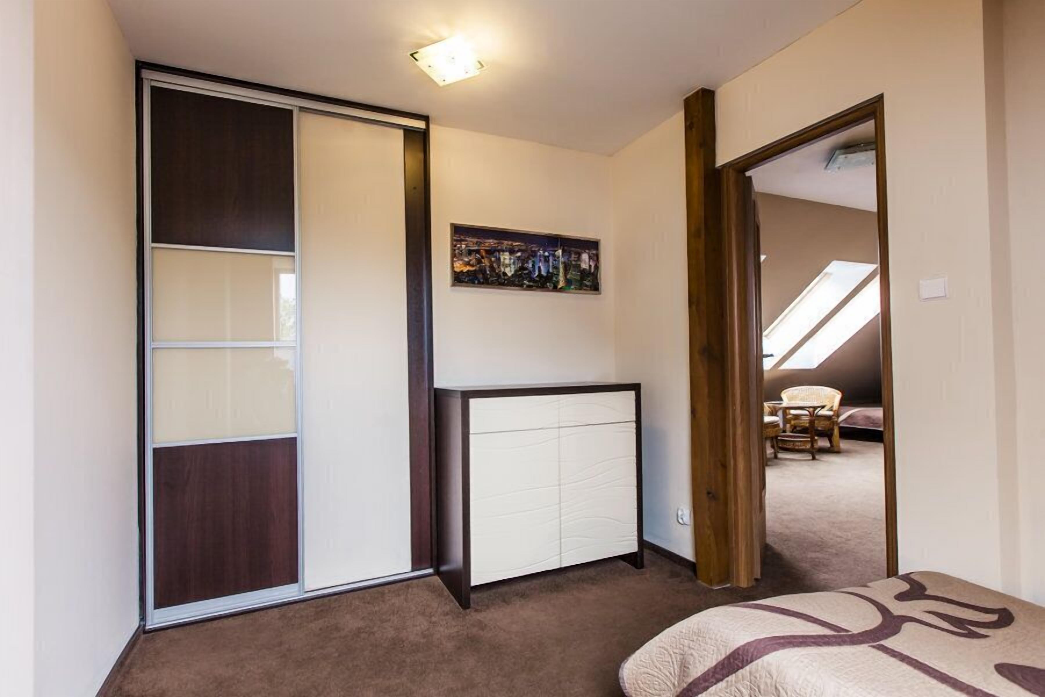 A bedroom with a closet, a bed, and a painting on the wall.