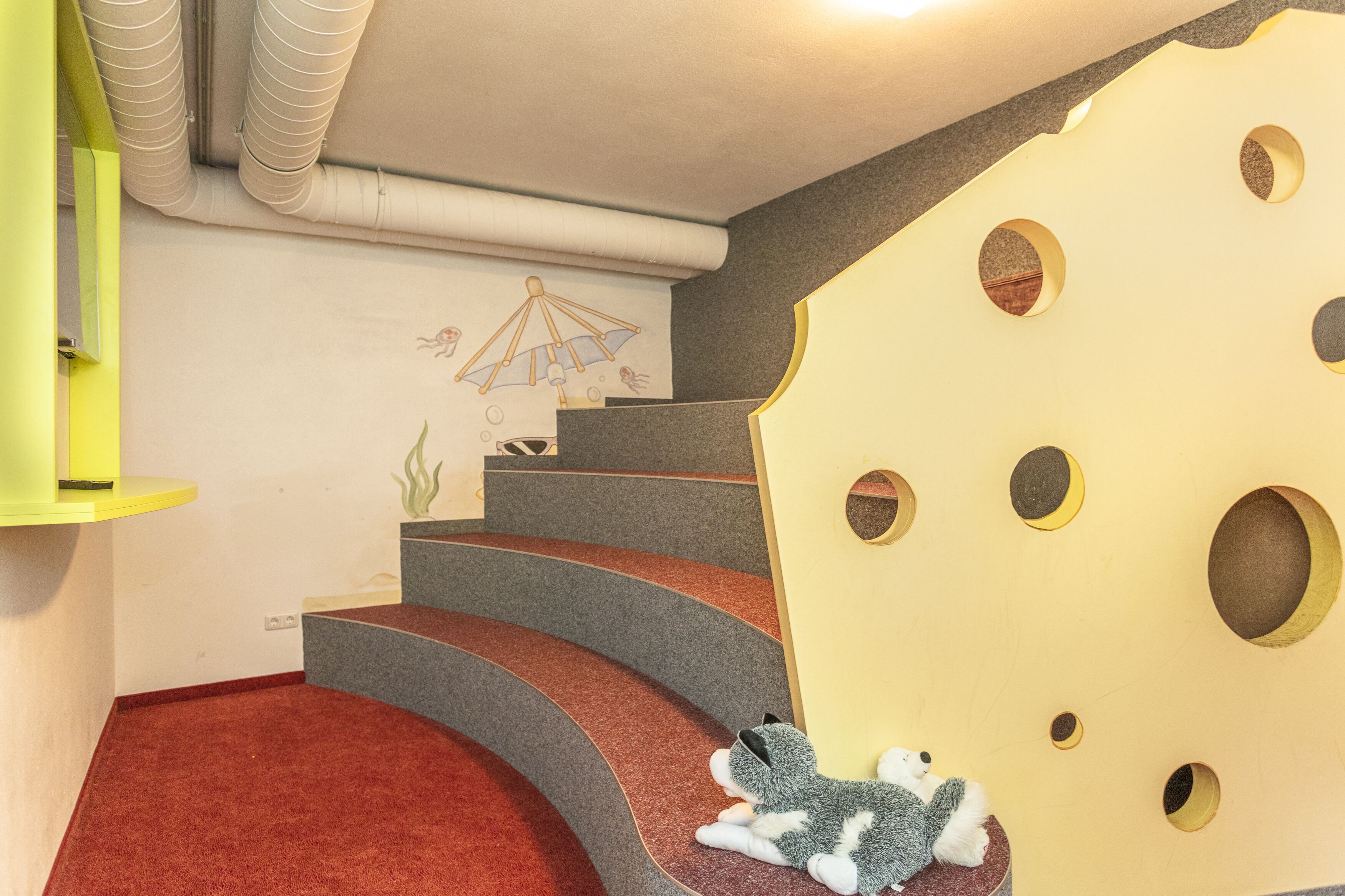 A staircase with red carpet steps and a wall with a large cheese decoration.