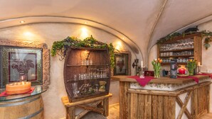 A rustic bar area with wooden shelves, glassware, and a candle centerpiece. - Hotel Wenger Alpenhof (Werfenweng)