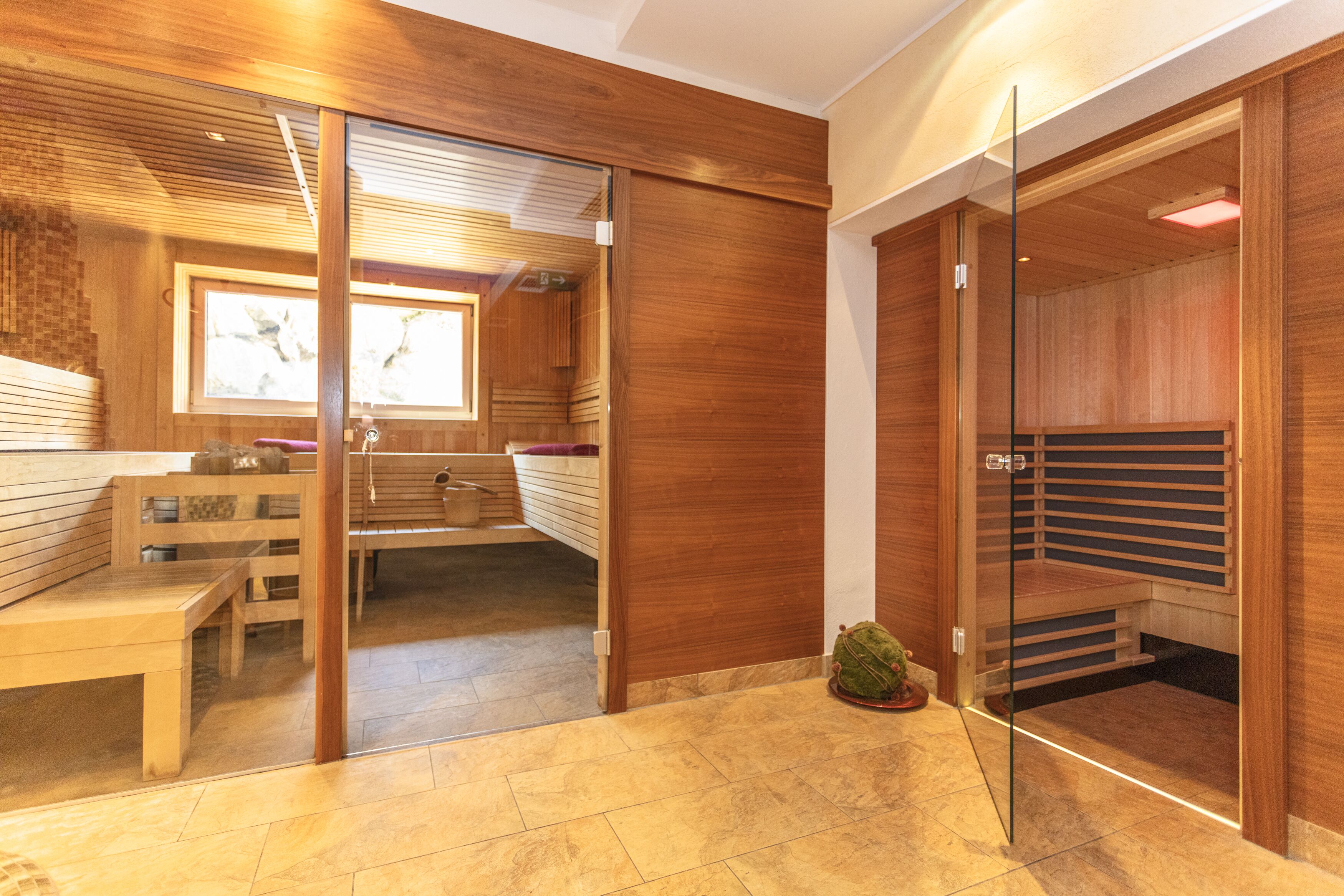 Un spa moderno con paneles de madera, un banco y una puerta de vidrio que da a una zona de sauna.