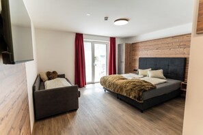Un dormitorio moderno con cama, sofá y puerta corrediza de vidrio que da a un balcón.