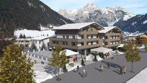 A modern building with a ski resort backdrop, featuring a central courtyard with trees and a bike path. - Hotel Wenger Alpenhof (Werfenweng)