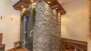 A stone wall with a glass door, wooden ceiling beams, and a metal railing. - Hotel Wenger Alpenhof (Werfenweng)