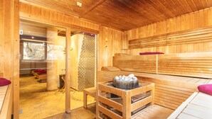A wooden sauna room with benches, a bench with a hot tub, and a small table with a hot tub. - Hotel Wenger Alpenhof (Werfenweng)
