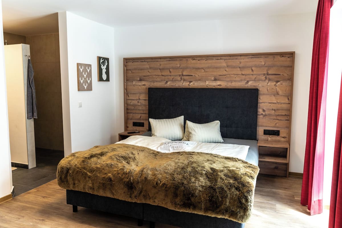 Een slaapkamer met een houten hoofdeinde, een bont plaid en twee kussens.
