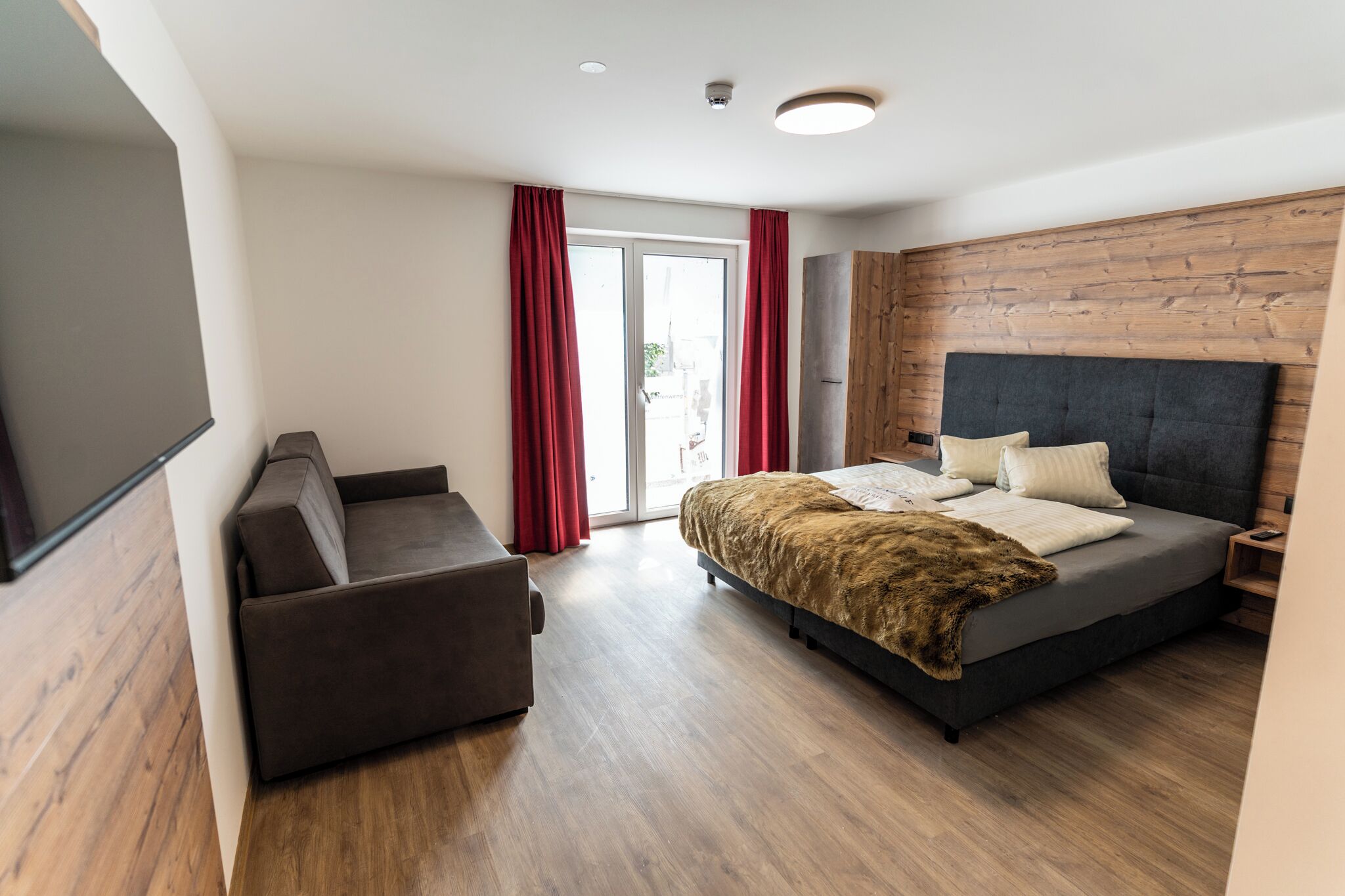 Un dormitorio moderno con una cama grande, un sofá y un cabecero de madera.