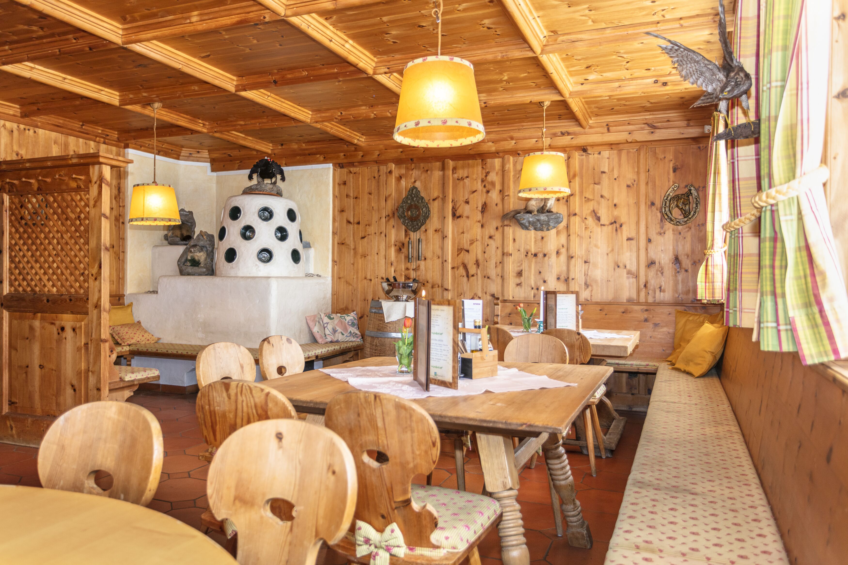A wooden interior with a dining area, wooden ceiling, and hanging lamps.