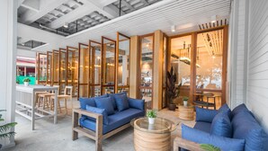 Un interior moderno con un sofá azul, mesas de madera y una zona de bar.