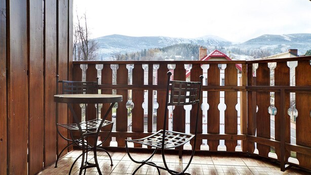 A wooden balcony with a table and two chairs, overlooking a snowy mountain landscape. - EverySky Nadrzeczna2 (Karpacz)