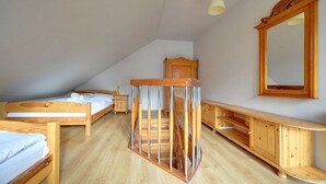 A bedroom with two wooden beds, a wooden crib, a wooden dresser, and a mirror on the wall. - EverySky Nadrzeczna2 (Karpacz)