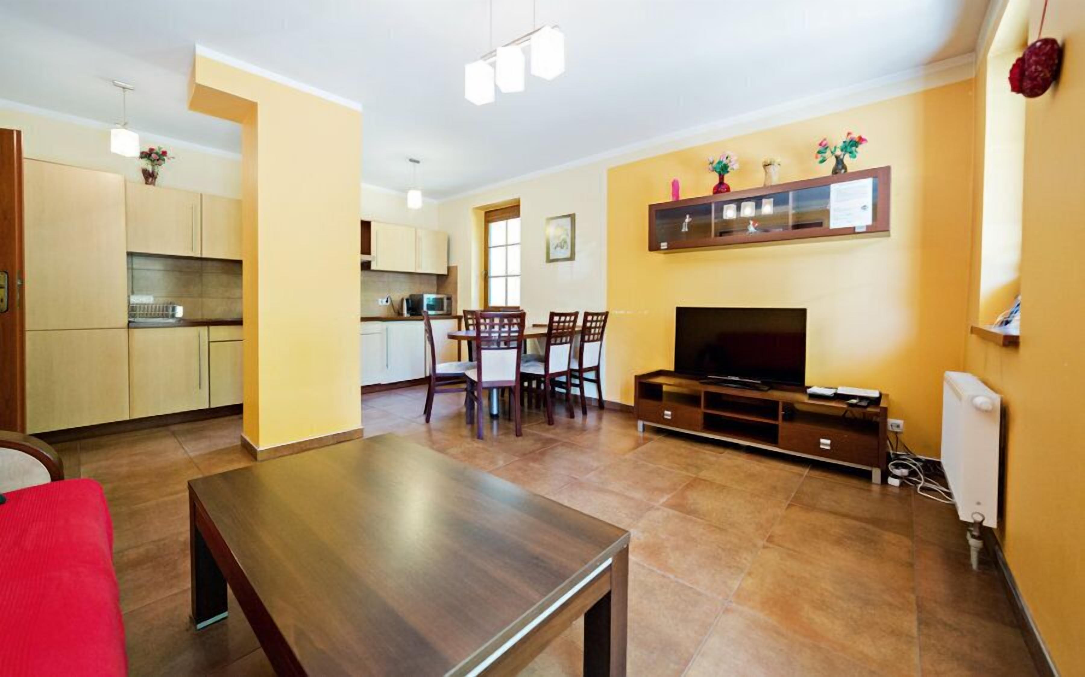 A living room with a TV, wooden furniture, and a dining area with chairs and a table.