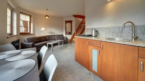 A modern kitchen with granite countertops, a stainless steel sink, and wooden cabinets. - EverySky Nadrzeczna2 (Karpacz)