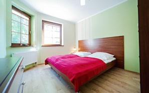 A bedroom with a wooden bed, a radiator, a window, and a desk. - EverySky Nadrzeczna2 (Karpacz)