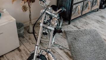 Ein Motorrad in einem Raum mit Holzboden, einem grauen Teppich und einer Kommode mit Schubladen.