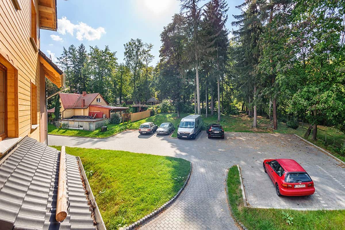 A residential driveway with parked cars and a house with a sloped roof.