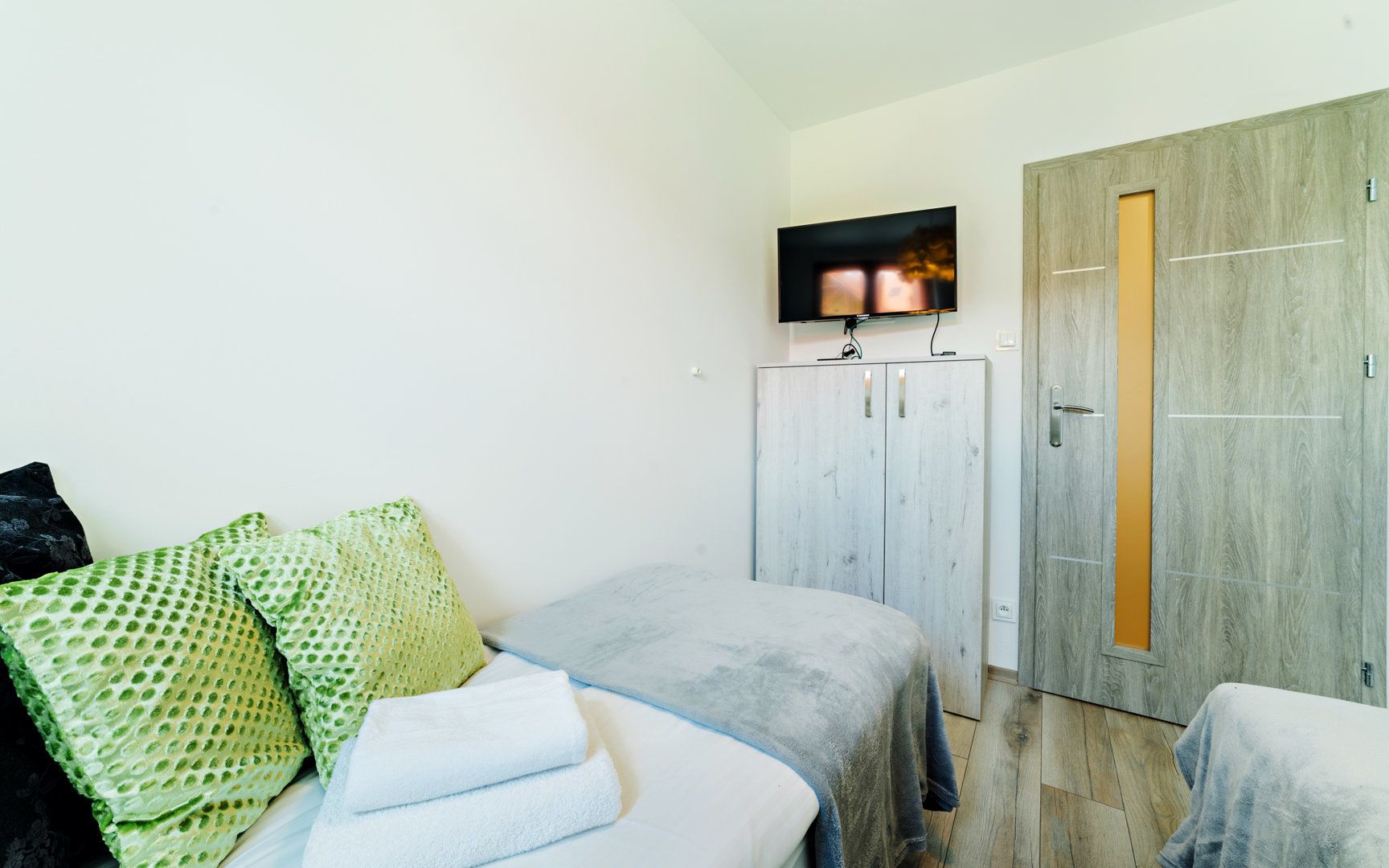 Un dormitorio con cama, televisor, armario y puerta.