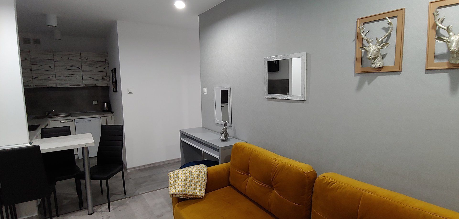 Ett kompakt bostadsutrymme med ett litet kök, en matplats och en soffa.