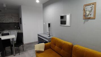 Ett kompakt bostadsutrymme med ett litet kök, en matplats och en soffa.