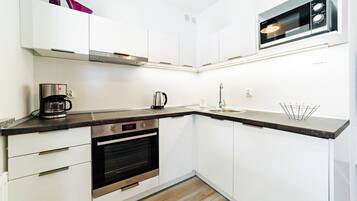 A modern kitchen with white cabinets, a stainless steel range, a built-in oven, a coffee maker, and a microwave.