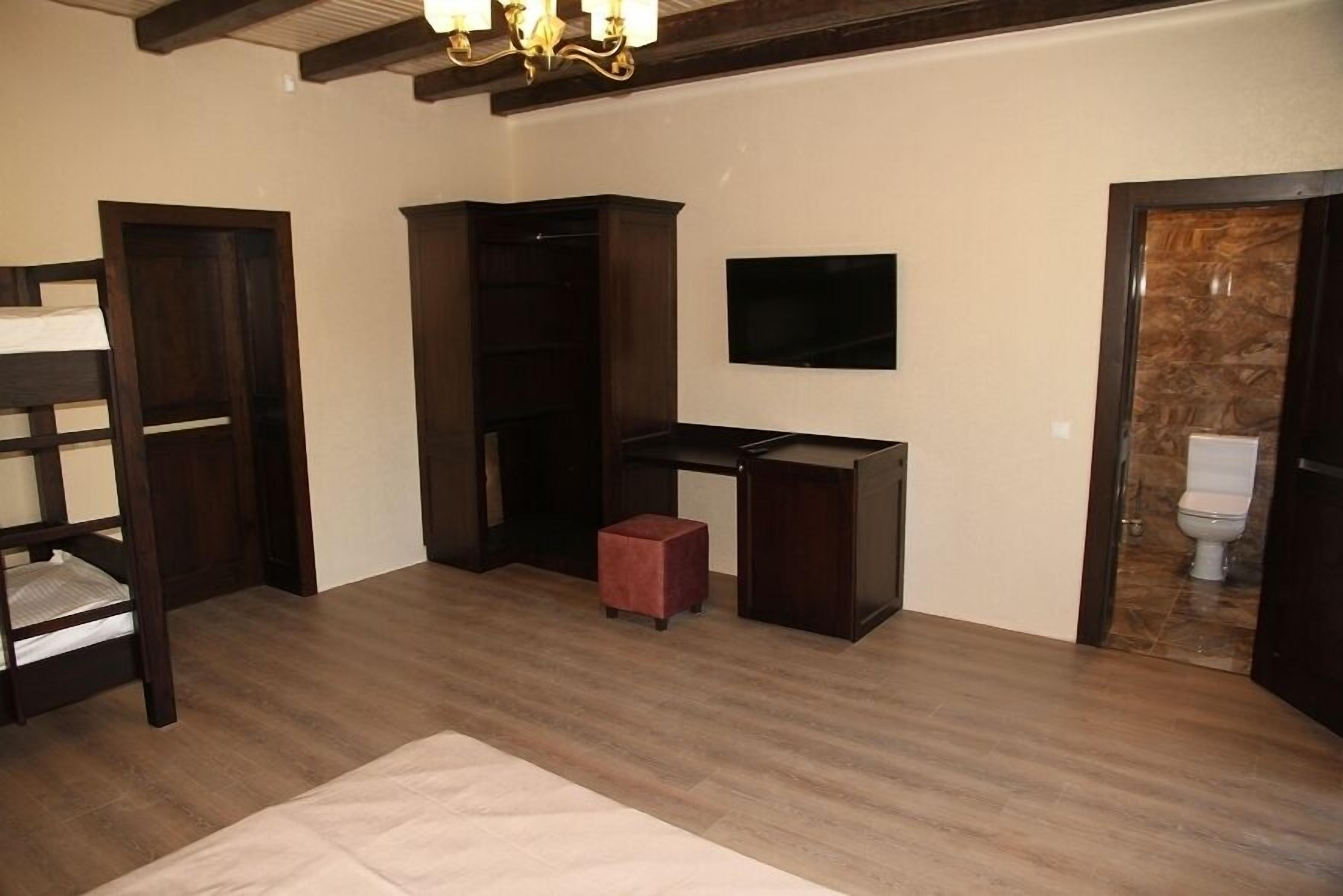 A room with a bunk bed, a desk, a television, and a small stool.