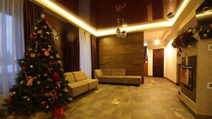 Ein modernes Wohnzimmer mit einem großen Weihnachtsbaum, einer Couch und einem Kamin.