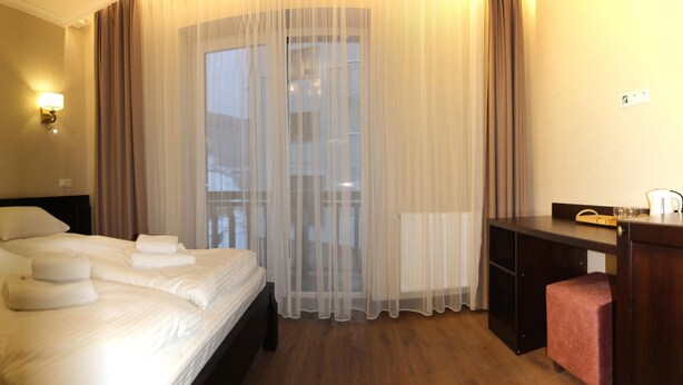 Ein Hotelzimmer mit einem großen Bett, zwei Nachttischlampen, einem Schreibtisch und einem Stuhl.