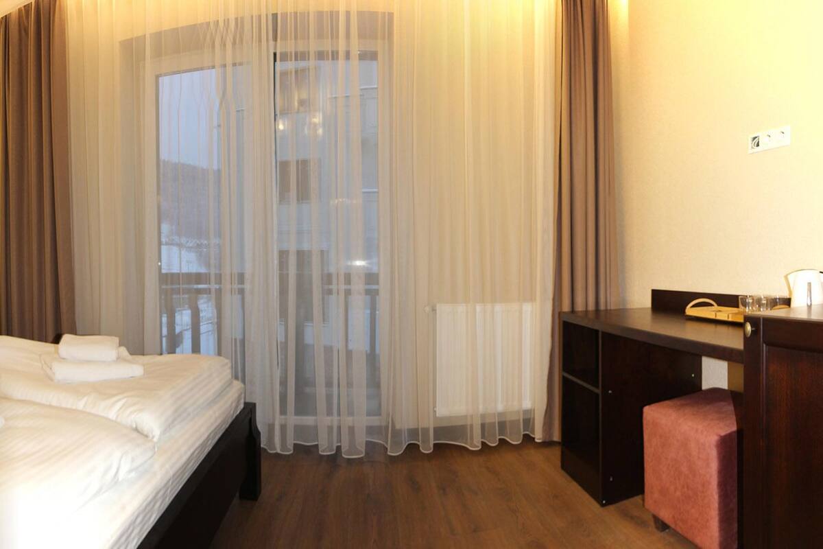 A hotel room with a large bed, two bedside lamps, a desk, and a chair.