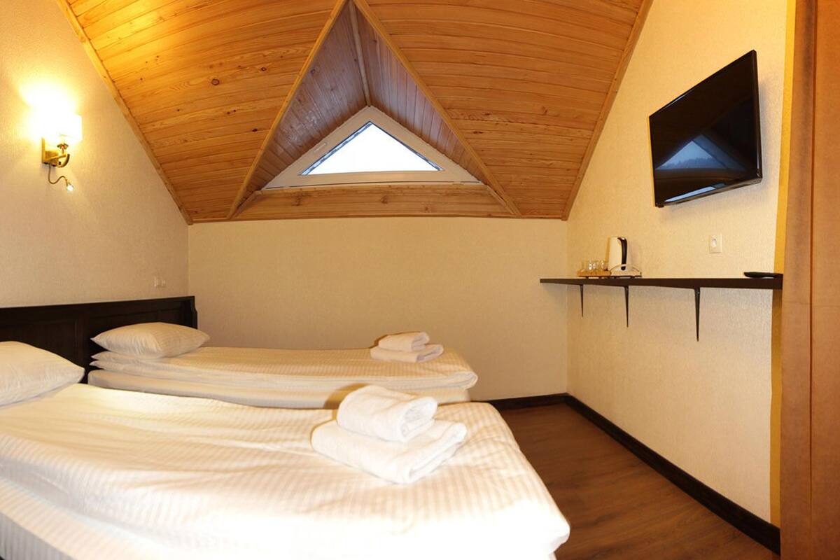 A room with two beds, a skylight, a TV, and a shelf with toiletries.