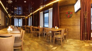 Ein Restaurant mit Holzwänden, großen Fenstern und einem Kamin.