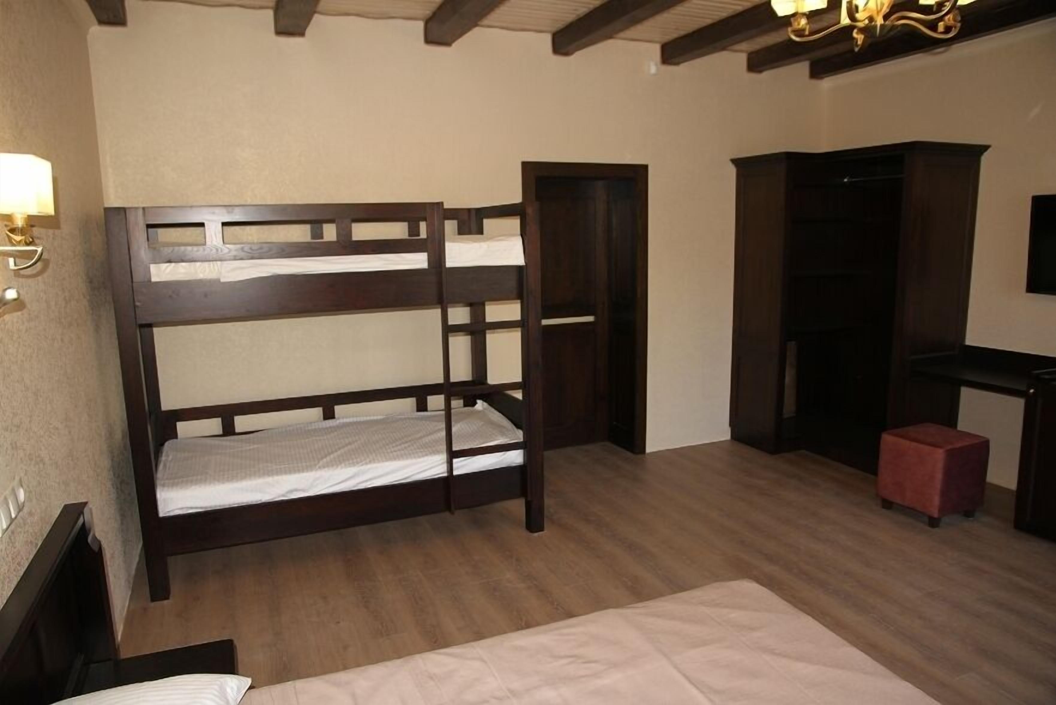Une chambre avec un lit superposé, un petit tabouret rouge, un bureau avec une chaise et une étagère fixée au mur.