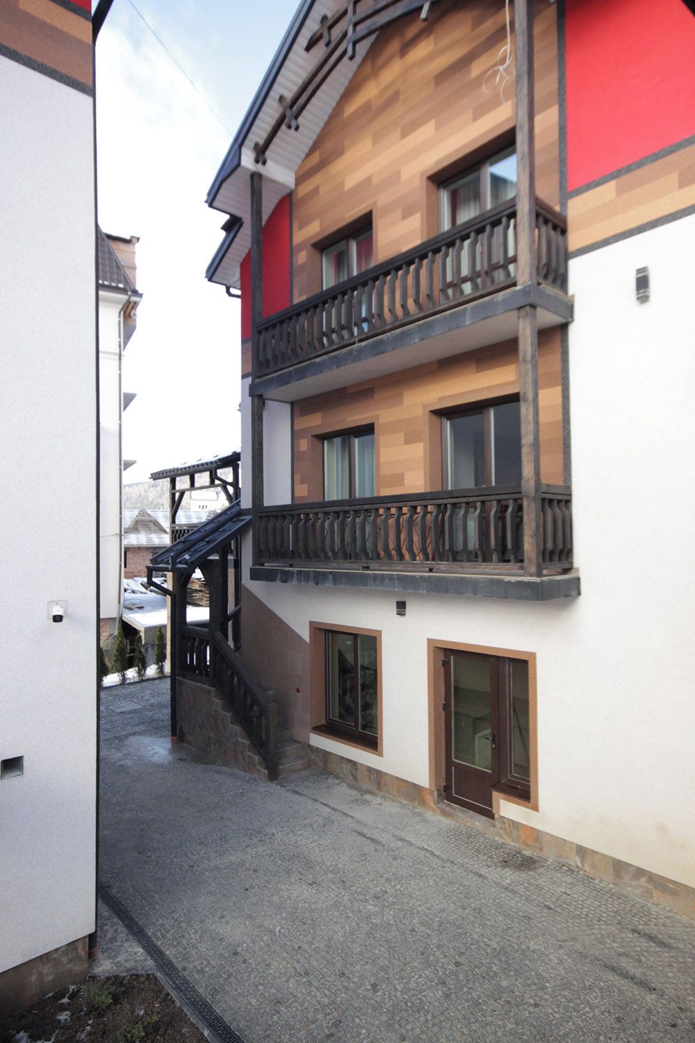 Un edificio de varios pisos con fachada de madera, balcones y una escalera que conduce a la entrada.