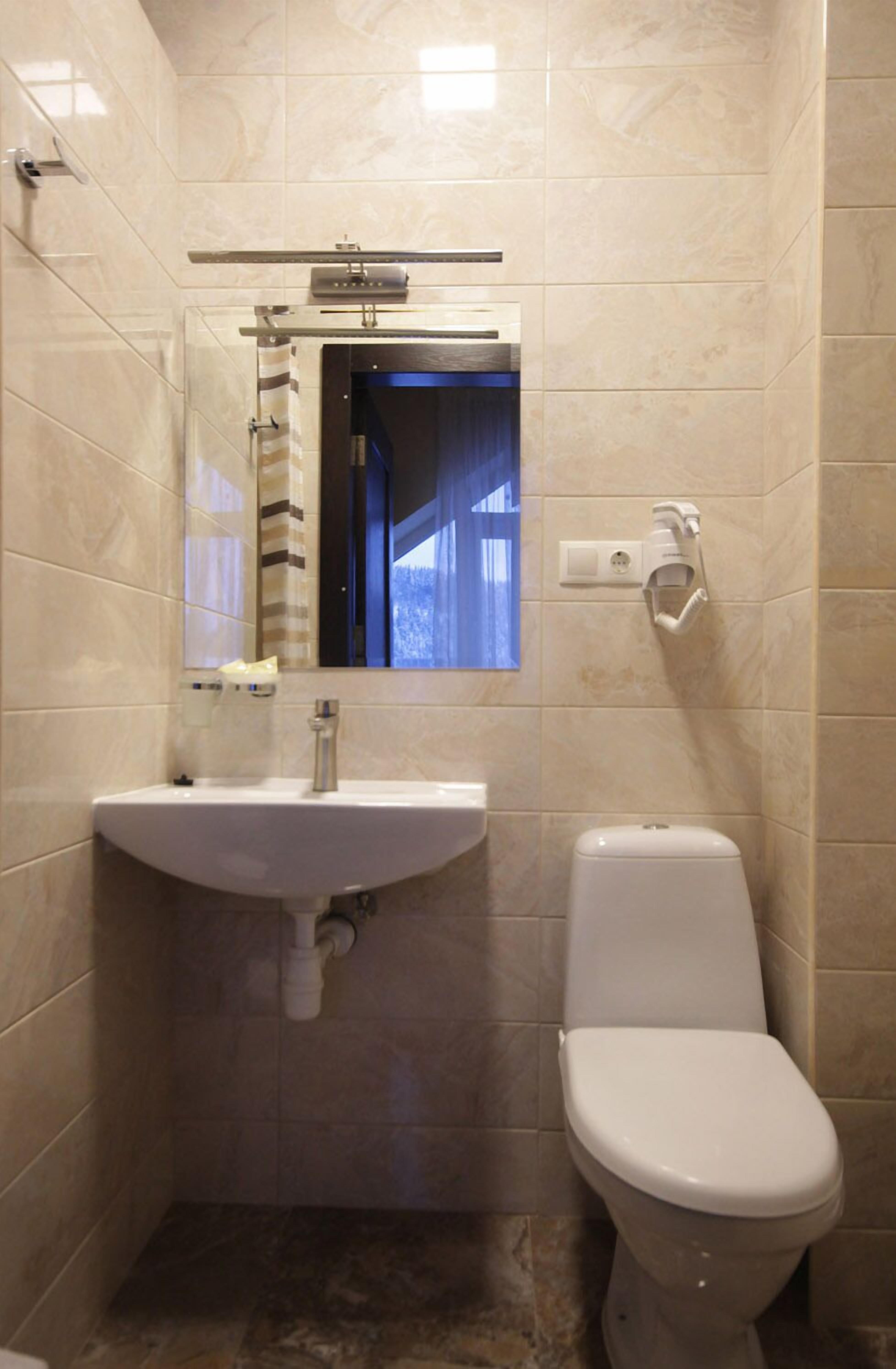 Un baño con lavamanos, espejo e inodoro.