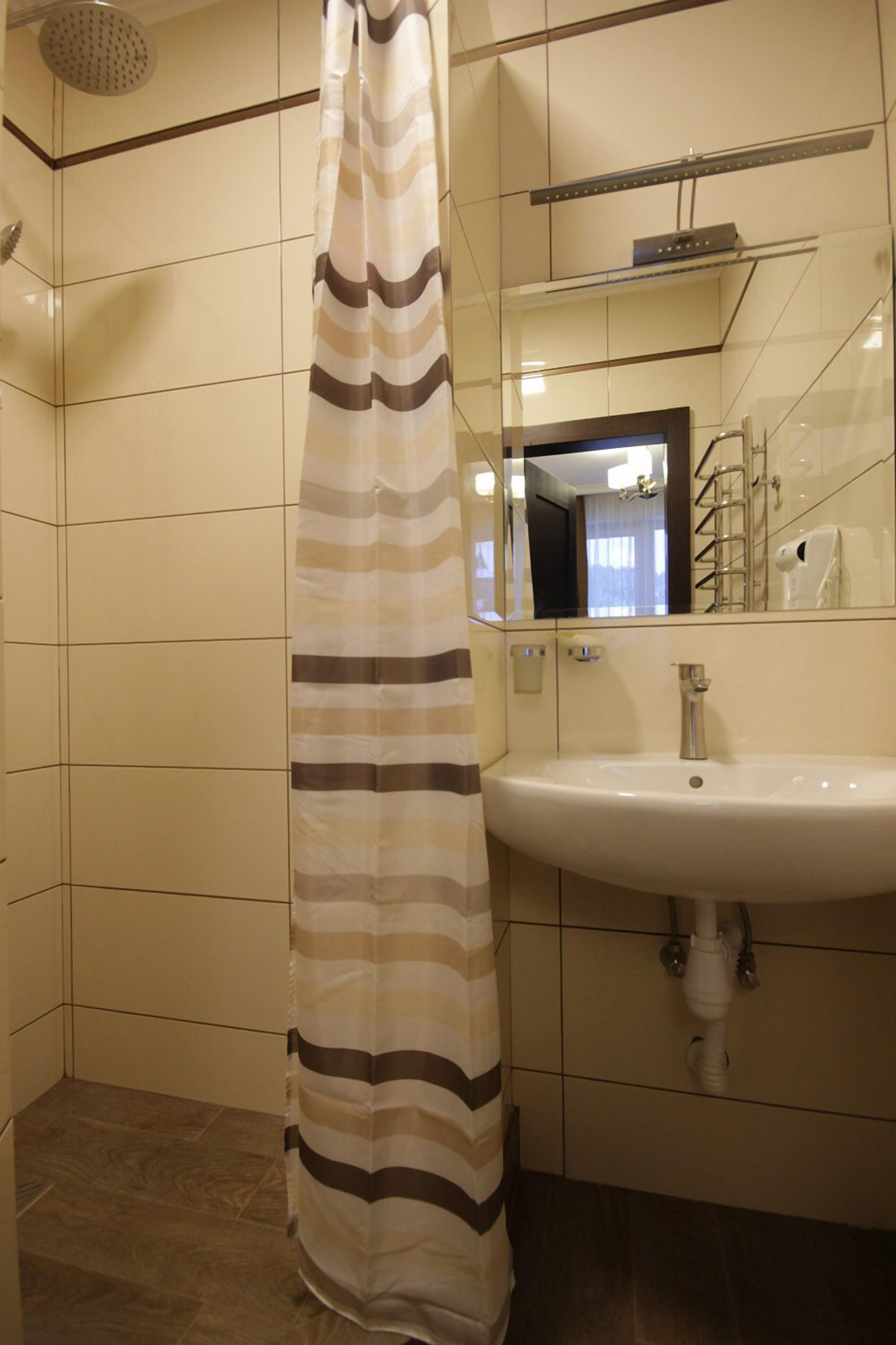 Un baño con cortina de ducha, lavabo y espejo.