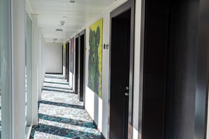 Un pasillo con puertas, un suelo estampado y un techo con luces empotradas.