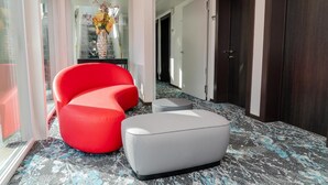 Un vestíbulo moderno con un sofá rojo, un otoman gris y una alfombra estampada.