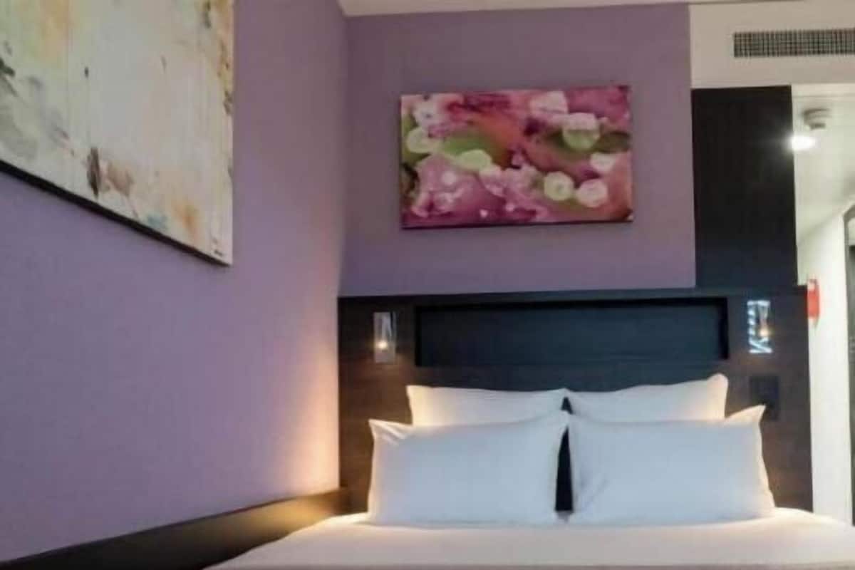 Ein Schlafzimmer mit einem Bett, einem Kopfteil, einem Wandbild und einer Tür.