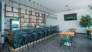 Een bar met een marmeren toonbank, verschillende barkrukken en een divers assortiment flessen.