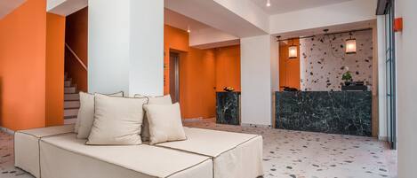 Un vestíbulo moderno con un sofá, un mostrador de recepción y una escalera.
