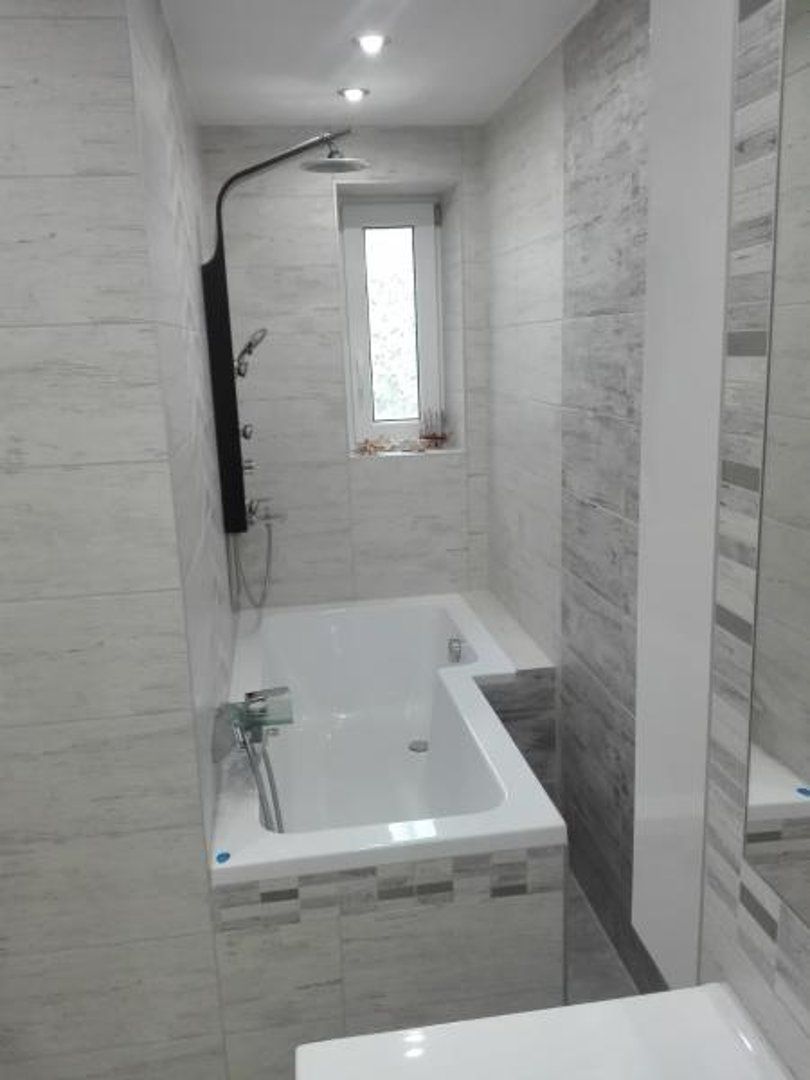 Une salle de bain avec une baignoire, une douche et une fenêtre.