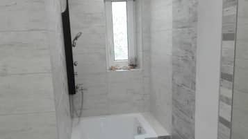Une salle de bain avec une baignoire, une douche et une fenêtre.