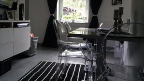 A modern kitchen with a dining table, clear chairs, a black and white striped rug, and a TV mounted on the wall. - EverySky Karpacz 3 Maja 66 (Karpacz)